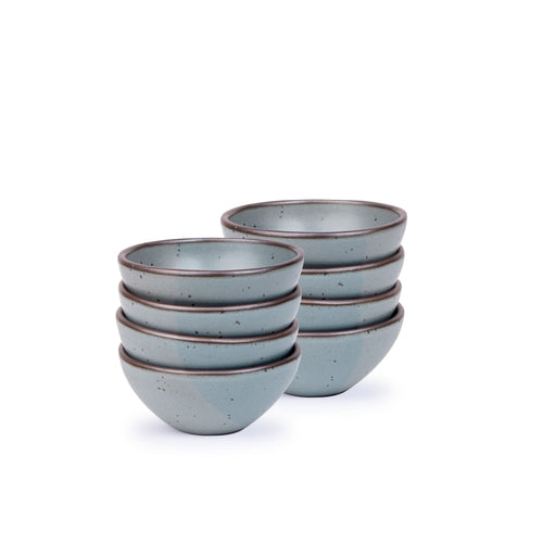 A stack of 8 small dessert sized rounded ceramic bowls in a blue-grey color featuring iron speckles and an unglazed rim