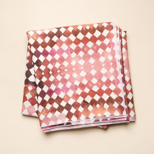 Watercolor diamond-patterned tablecloth in warm burgundy and pink tones