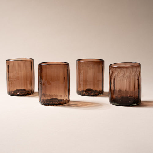 Four taller amber-brown glass tumblers with vertical ridges, set against a neutral background.
