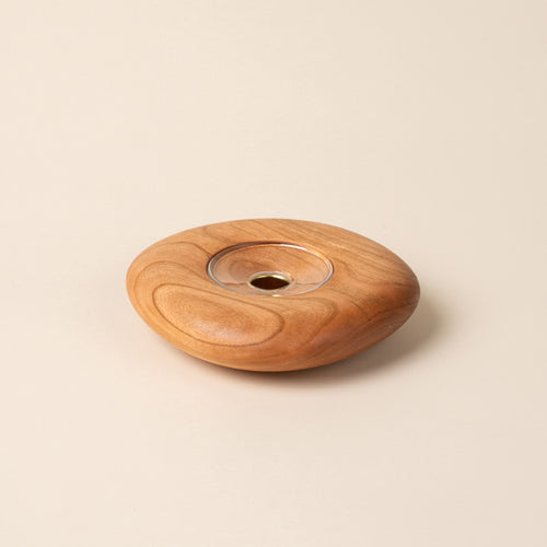 Large round cherry wood candle holder with visible grain and a glass insert in the center, displayed against a neutral background.