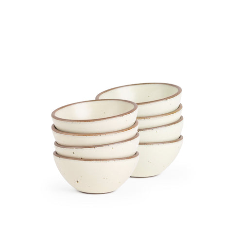 A stack of 4 small dessert sized rounded ceramic bowls in a warm off-white color featuring iron speckles and an unglazed rim