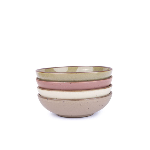 A stack of 4 dinner-sized shallow ceramic bowls in a warm off-white, reflective dappled grey-green, warm pale brown and dusty mauve pink colors featuring iron speckles and an unglazed rim