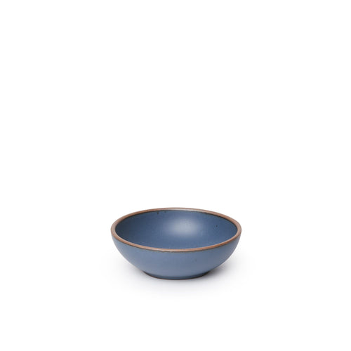 A small shallow ceramic bowl in a cool medium blue color featuring iron speckles and an unglazed rim