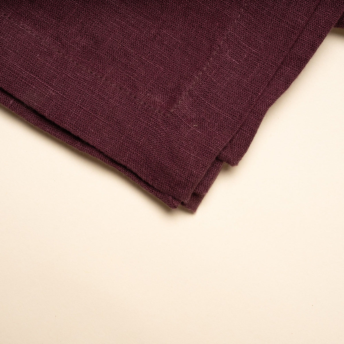 A folded linen tablecloth in a deep purple color