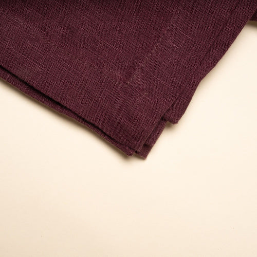 A folded linen tablecloth in a deep purple color