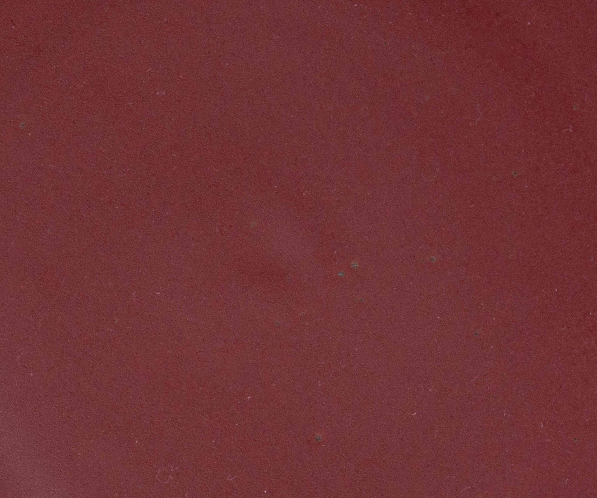 A closeup of a ceramic plate in a berry plum color featuring iron speckles