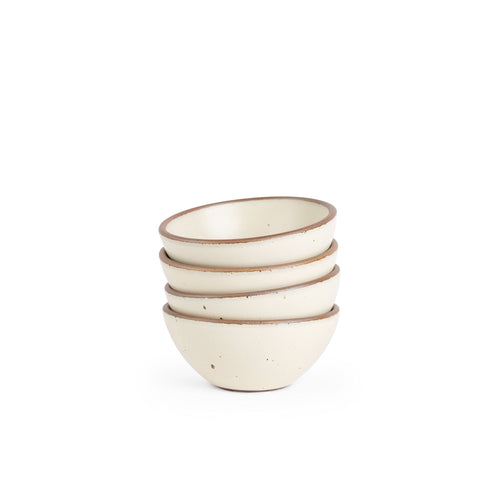 A stack of 4 small dessert sized rounded ceramic bowls in a warm, tan-toned, off-white color featuring iron speckles and an unglazed rim