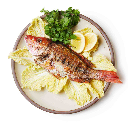 Fish spread on a large ceramic platter in a warm, tan-toned, off-white color featuring iron speckles and an unglazed rim