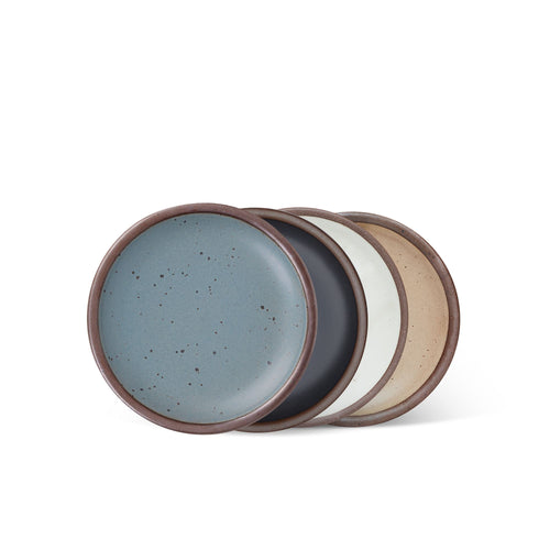 4 dessert sized ceramic plates in a blue-grey, graphite black, cool white, and warm pale brown color featuring iron speckles and an unglazed rim.