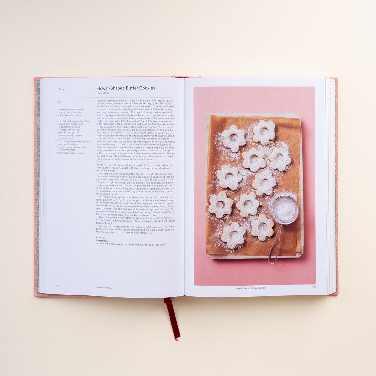 Open cookbook showing recipe text for flower-shaped butter cookies with photo of cookies dusted with powdered sugar.