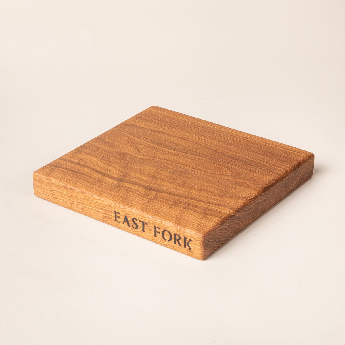 A square white oak cutting board on its side with an engraving on the edge that reads 'East Fork'