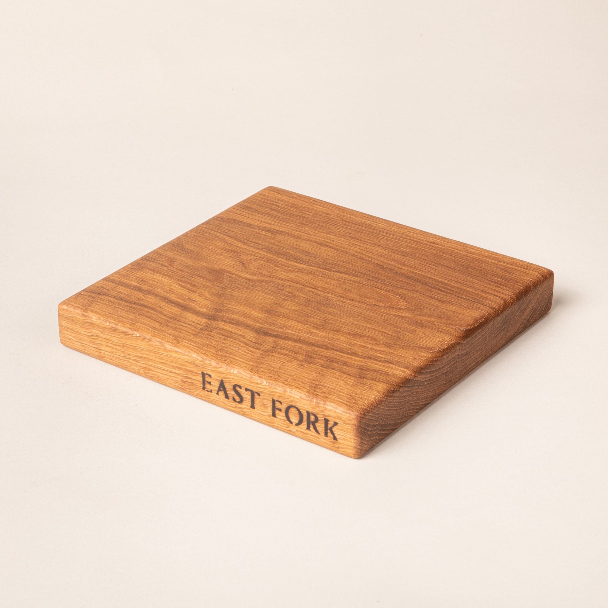 A square white oak cutting board on its side with an engraving on the edge that reads 'East Fork'