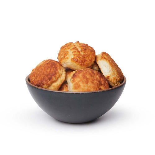 A large rounded ceramic bowl in a graphite black color featuring iron speckles and an unglazed rim, filled with biscuits