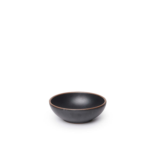 A small shallow ceramic bowl in a graphite black color featuring iron speckles and an unglazed rim
