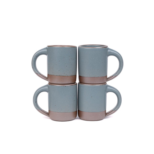 Four medium sized ceramic mugs with handles in a blue-grey color featuring iron speckles and unglazed rim