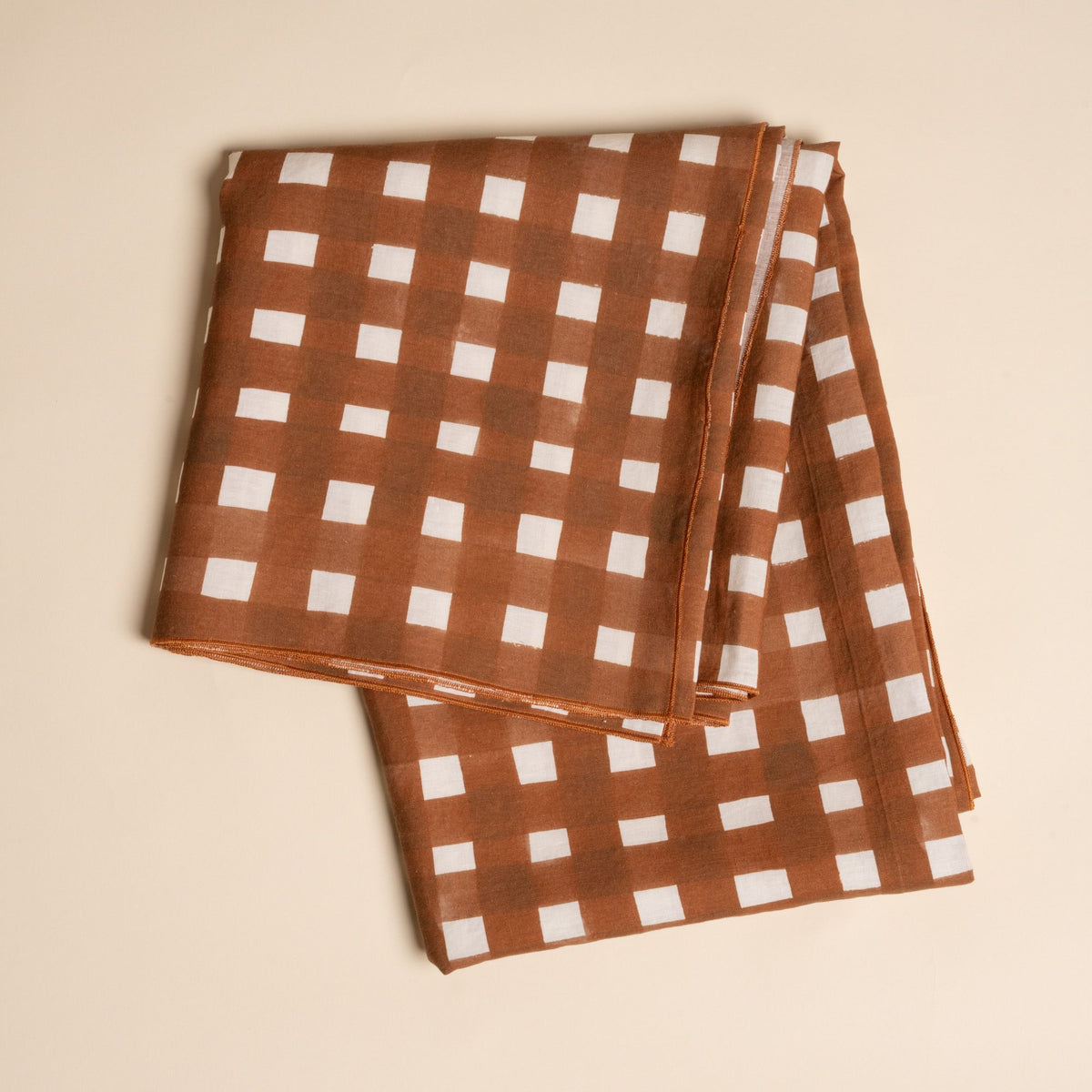 A folded tablecloth featuring a brown and white crosshatch pattern