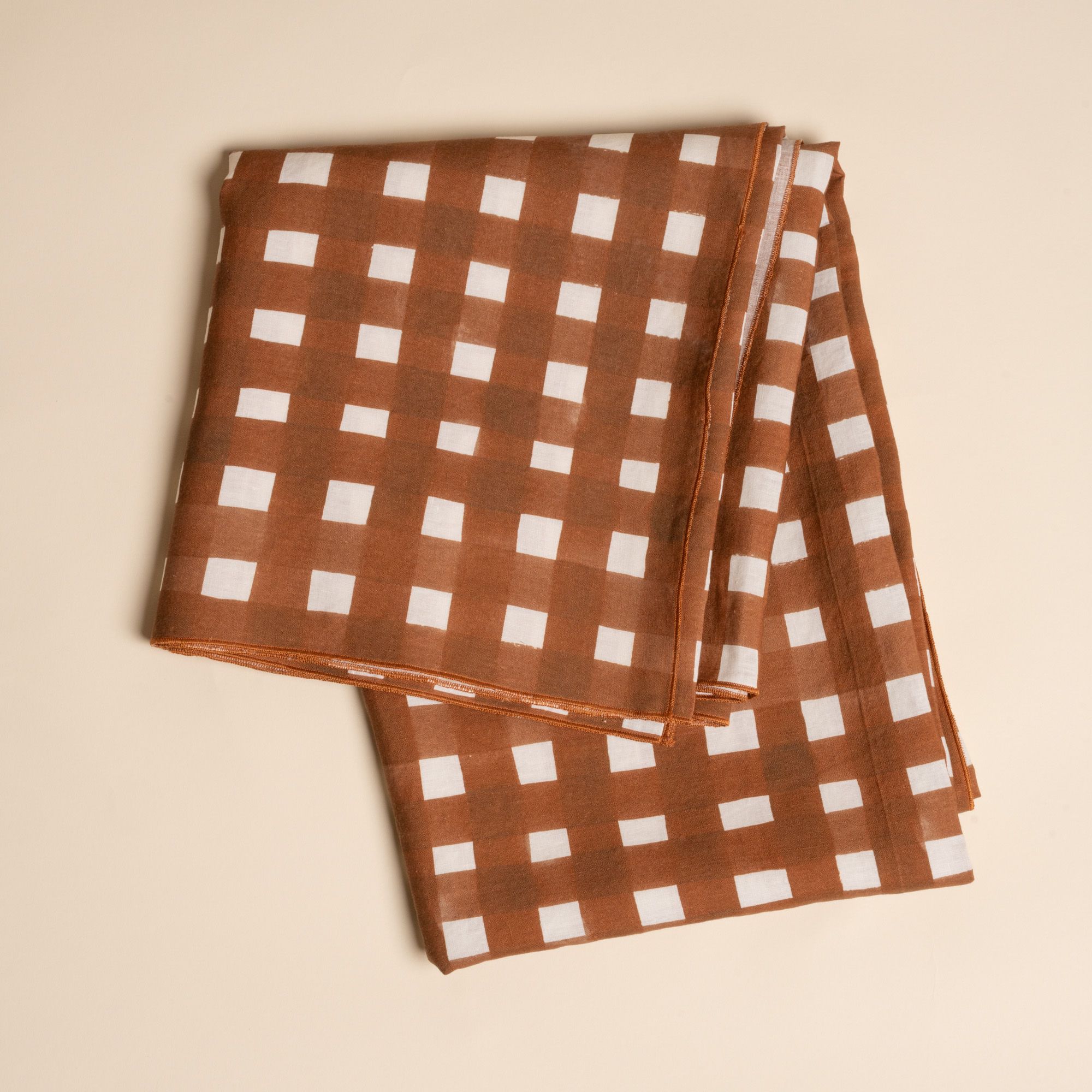 A folded tablecloth featuring a brown and white crosshatch pattern