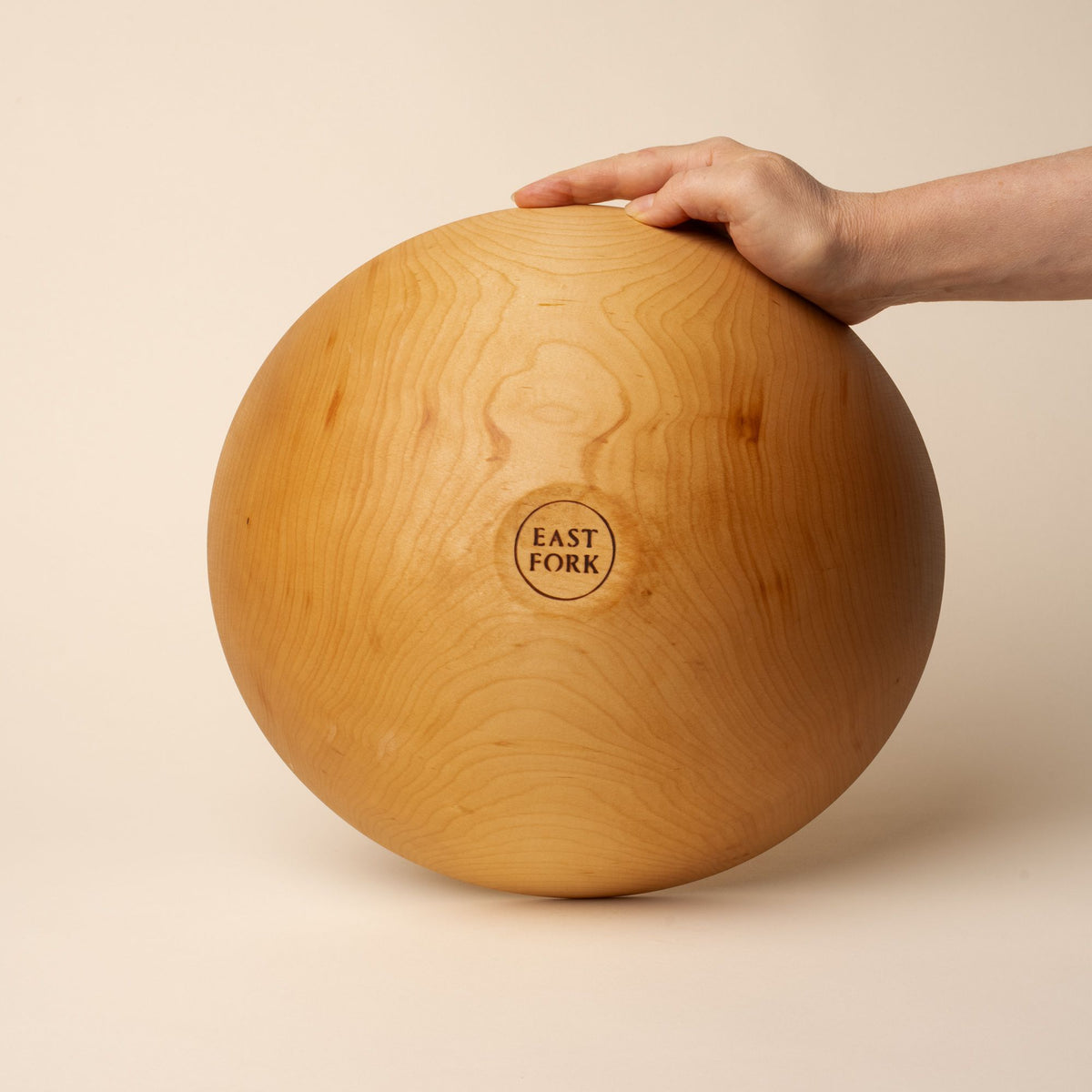 The bottom of a large maple wood bowl with a stamp that reads "East Fork"