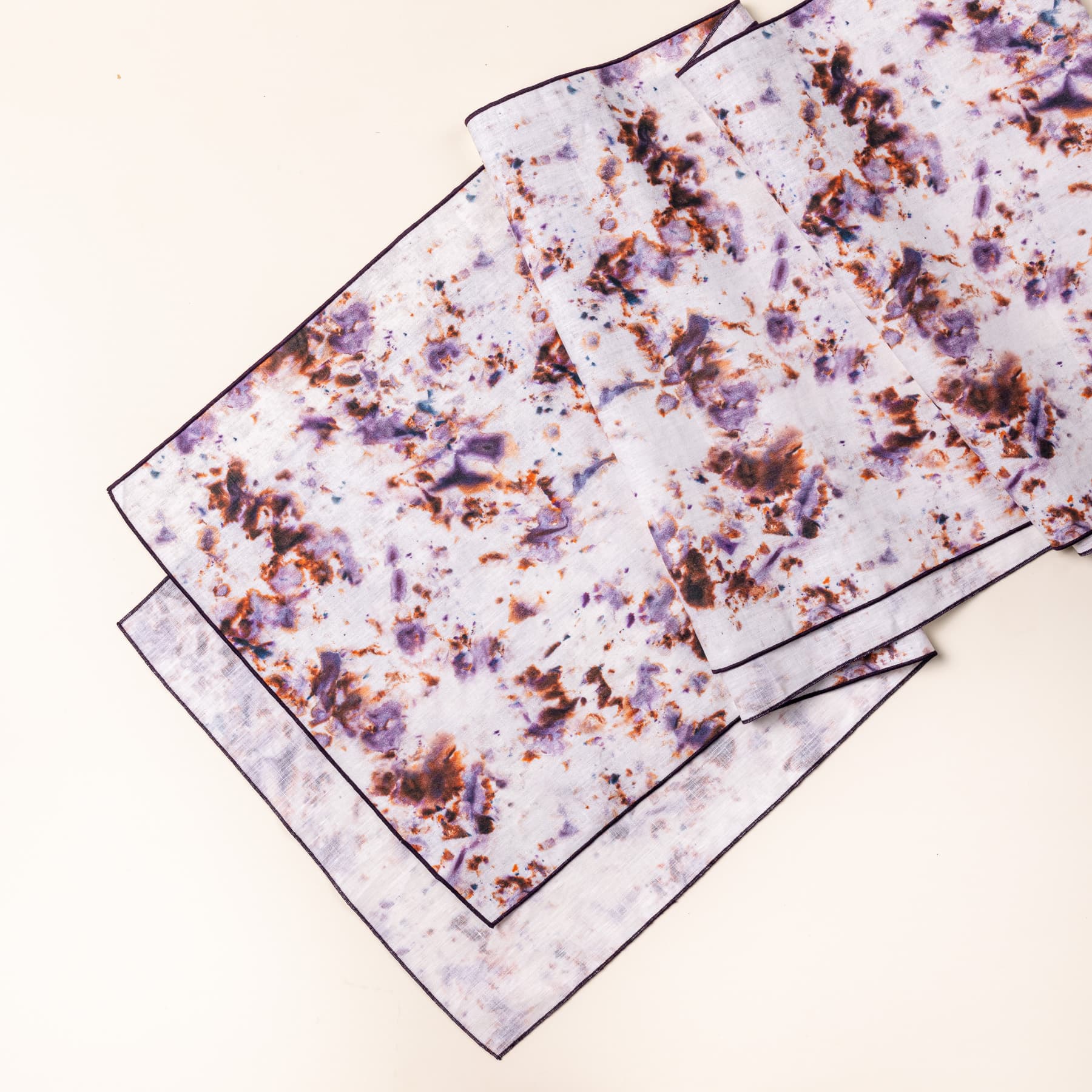 A table runner with a marble pattern featuring pink, purple, orange and white colors folded artfully