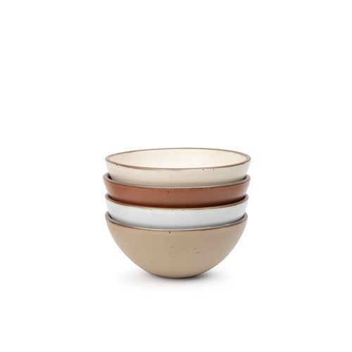 A stack of 4 medium sized rounded ceramic bowls in a cool terracotta, warm off-white cool white, and warm pale brown colors featuring iron speckles and an unglazed rim