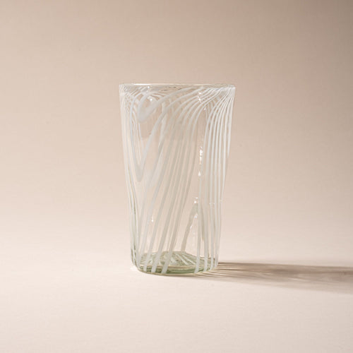 Clear pint glass with white diagonal swirl pattern against a neutral background.