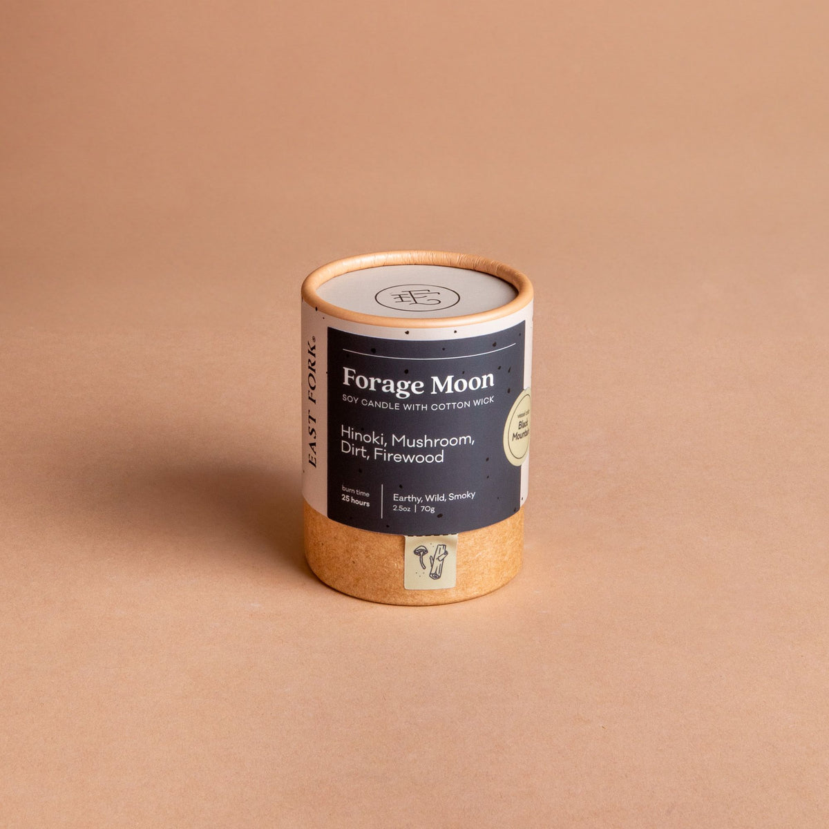 Small cardboard packaging tube with a candle inside with branding on it that says 'Forage Moon'