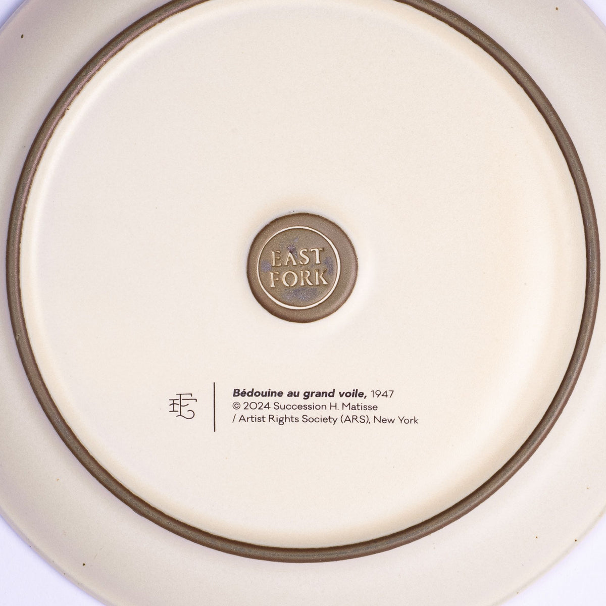 The back of a side plate with an East Fork stamp with a small decal of information about the artwork, Bédouine au grand voile, by Henri Matisse.