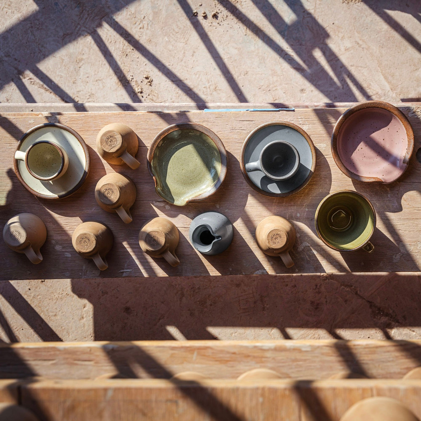 Shelves of unglazed espresso cups sitting with a finished Workshop pieces such as The Creamer, Sunday Morning Mug, Espresso Cup and Saucer and Spoon Rest.