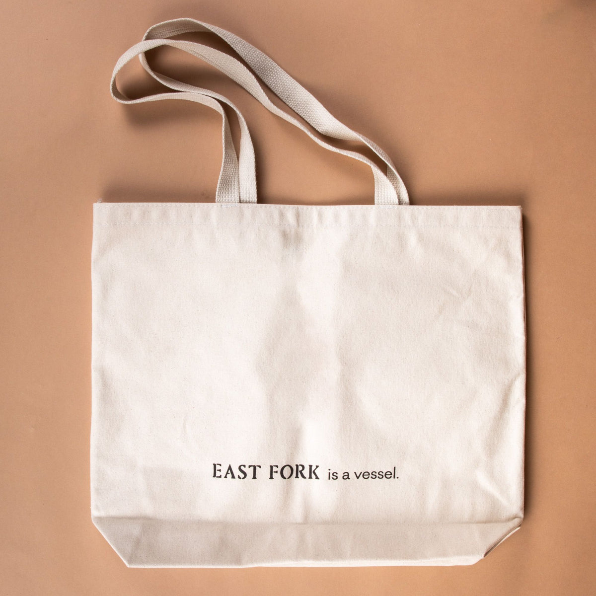 The back of a cream canvas tote with text that reads "East Fork is a vessel"