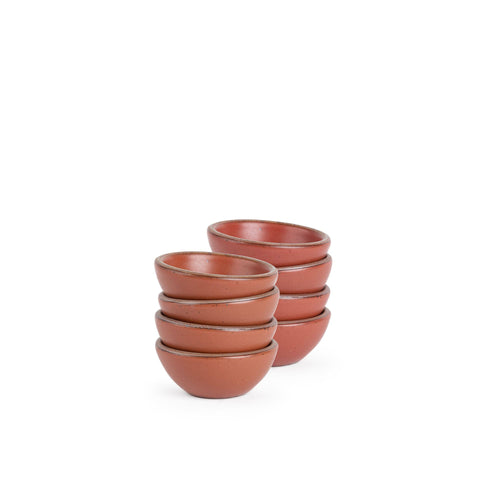 A stack of 8 tiny rounded ceramic bowls in a cool burnt terracotta color featuring iron speckles and an unglazed rim