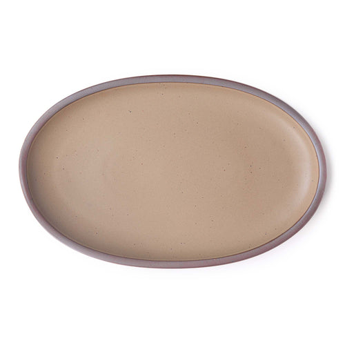 A large oval ceramic platter in a taupe color featuring iron speckles and an unglazed rim