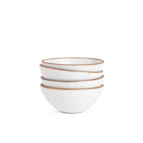 A stack of 4 medium rounded ceramic bowls in a cool white color featuring iron speckles and an unglazed rim