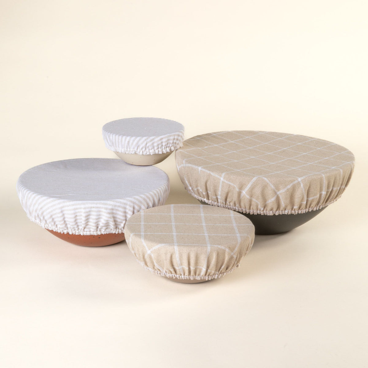 Mixing bowl, popcorn bowl, soup bowl, and ice cream bowl with linen bowl covers on them in neutral and cool white patterns.