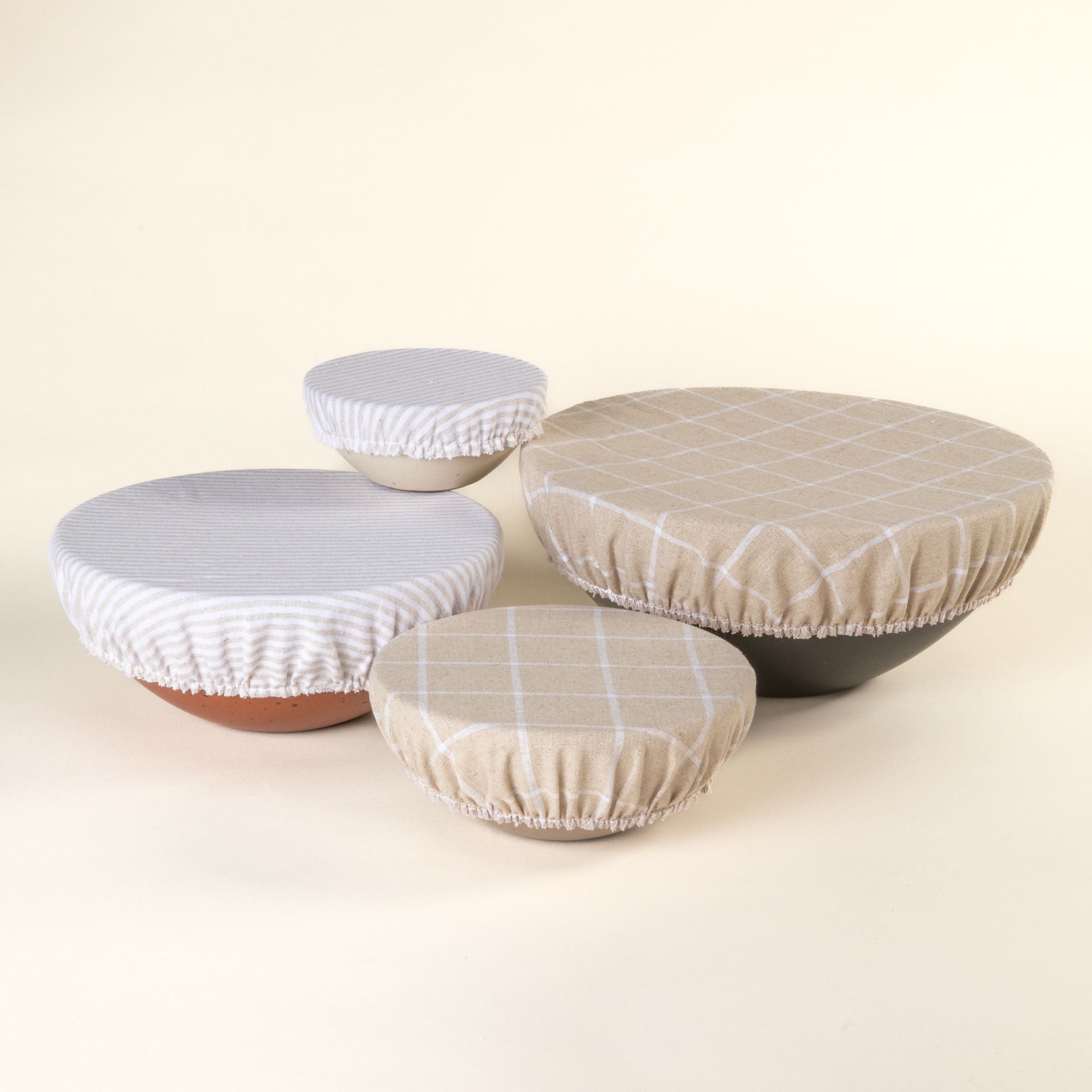 Mixing bowl, popcorn bowl, soup bowl, and ice cream bowl with linen bowl covers on them in neutral and cool white patterns.