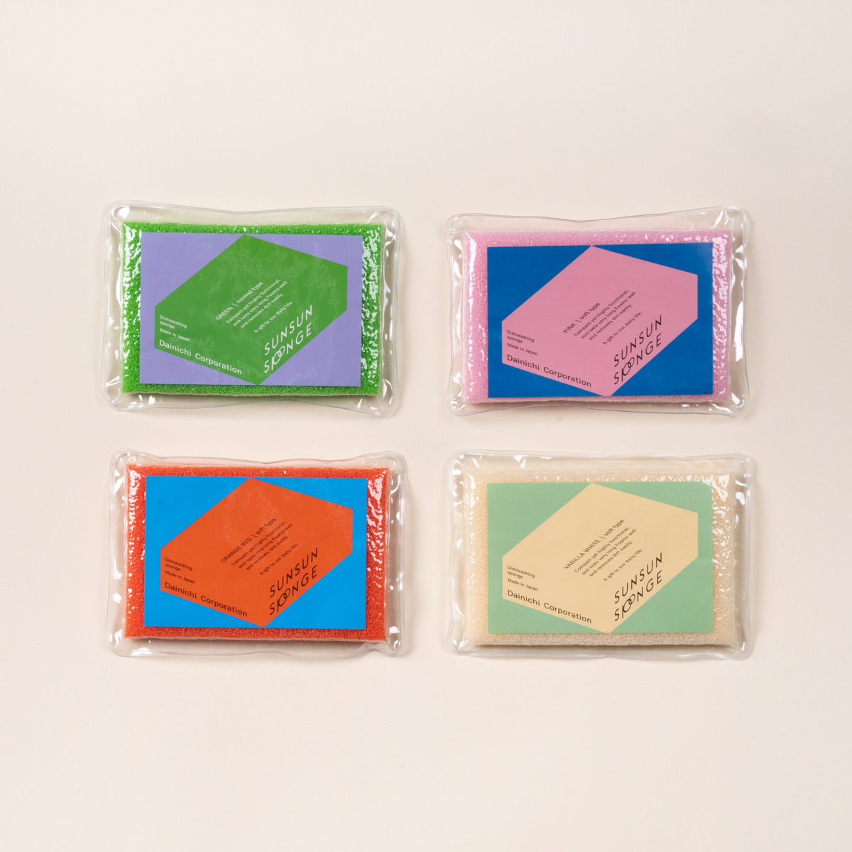 Four packaged SUNSUN dish sponges in green, pink, orange, and cream, arranged in a grid on a light background.