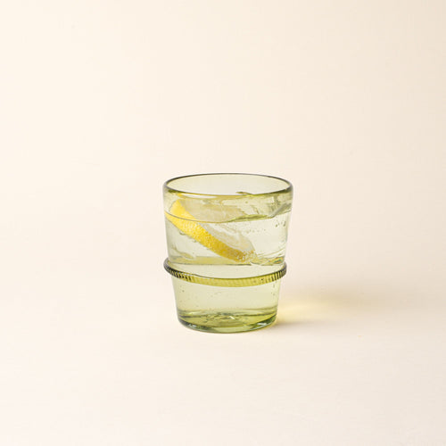 An olive short recycled glass tumbler with a ridged band detail, filled with water and a lemon slice.