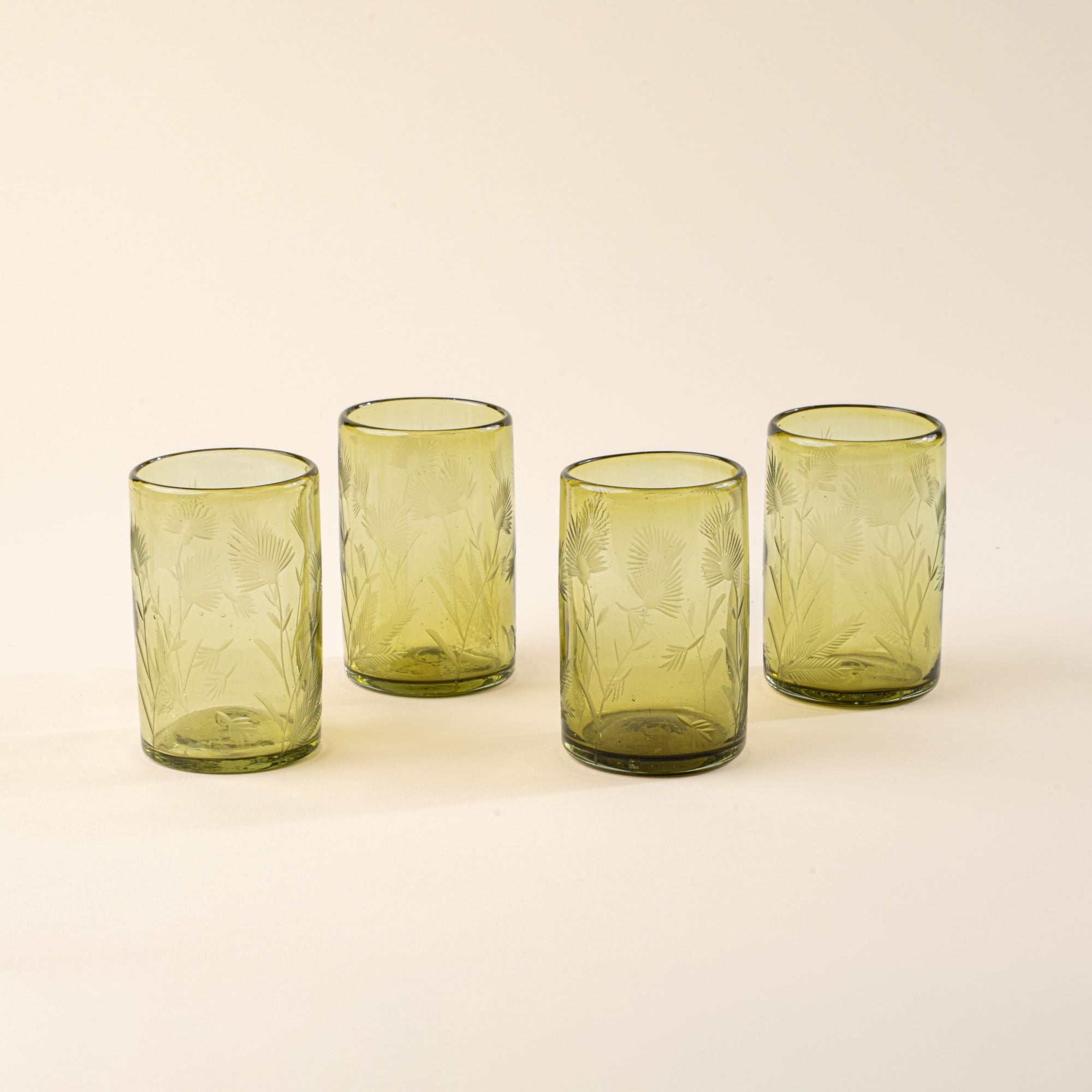 Four olive tumbler glasses made of recycled glass with etched thistle designs on it