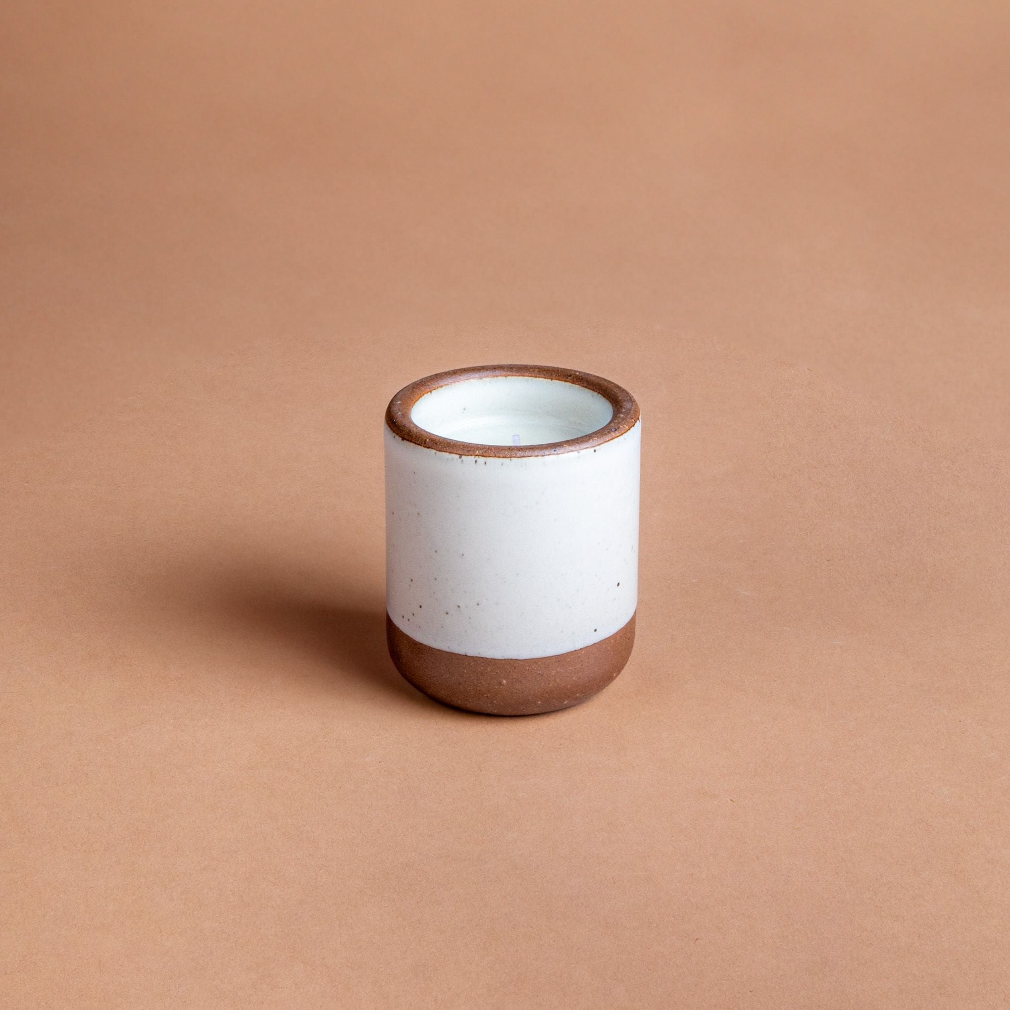Small ceramic vessel in a cool white color with candle inside.