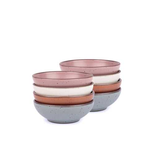 A stack of 8 small shallow ceramic bowls in a cool terracotta, warm off-white, blue-grey and dusty mauve pink colors featuring iron speckles and an unglazed rim