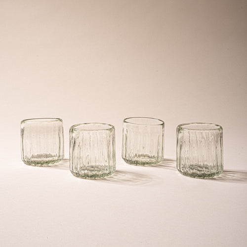Four clear textured glass tumblers with vertical ridges against a neutral background.