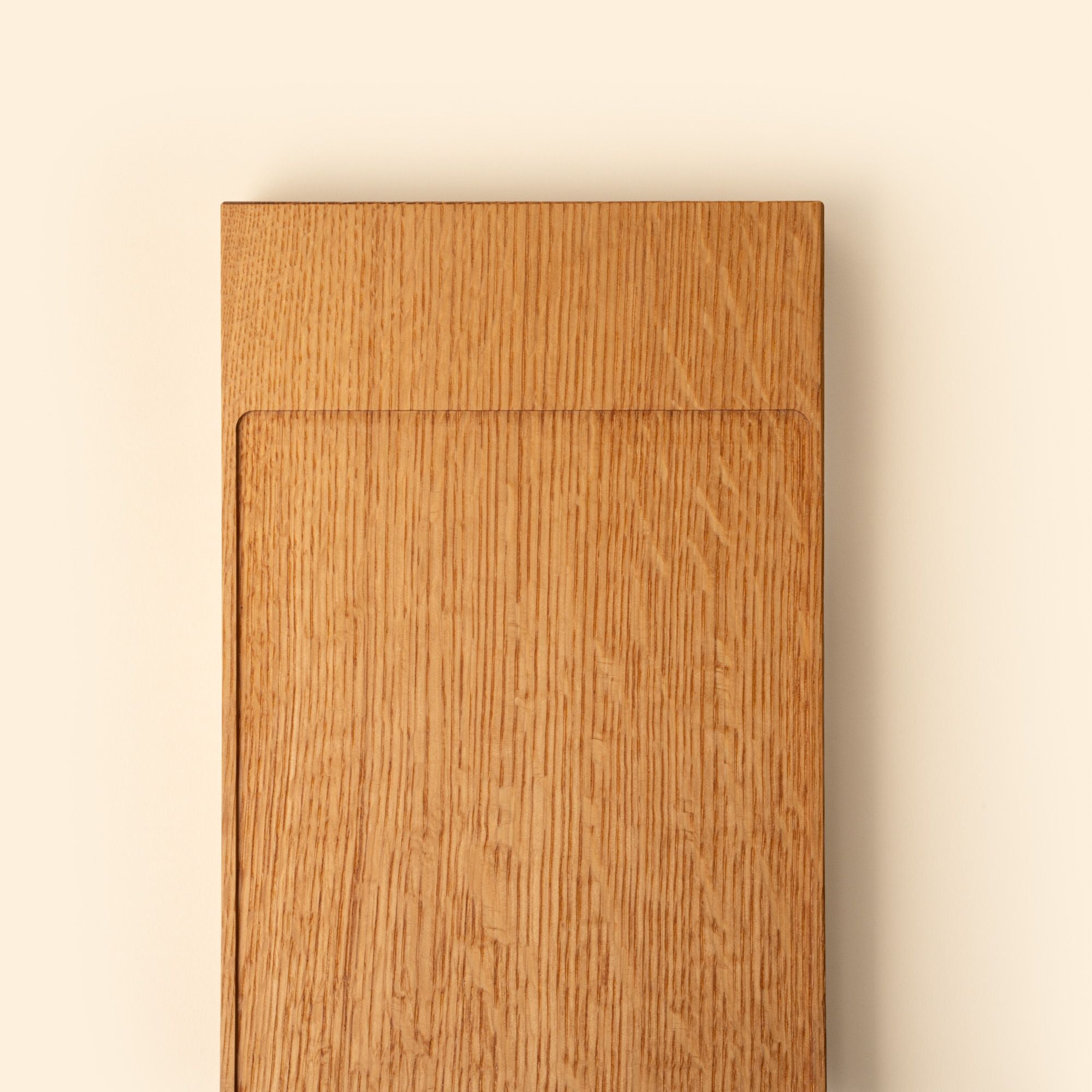 Close up of the end of a narrow rectangle of light oak wood with a vertical groove at either end