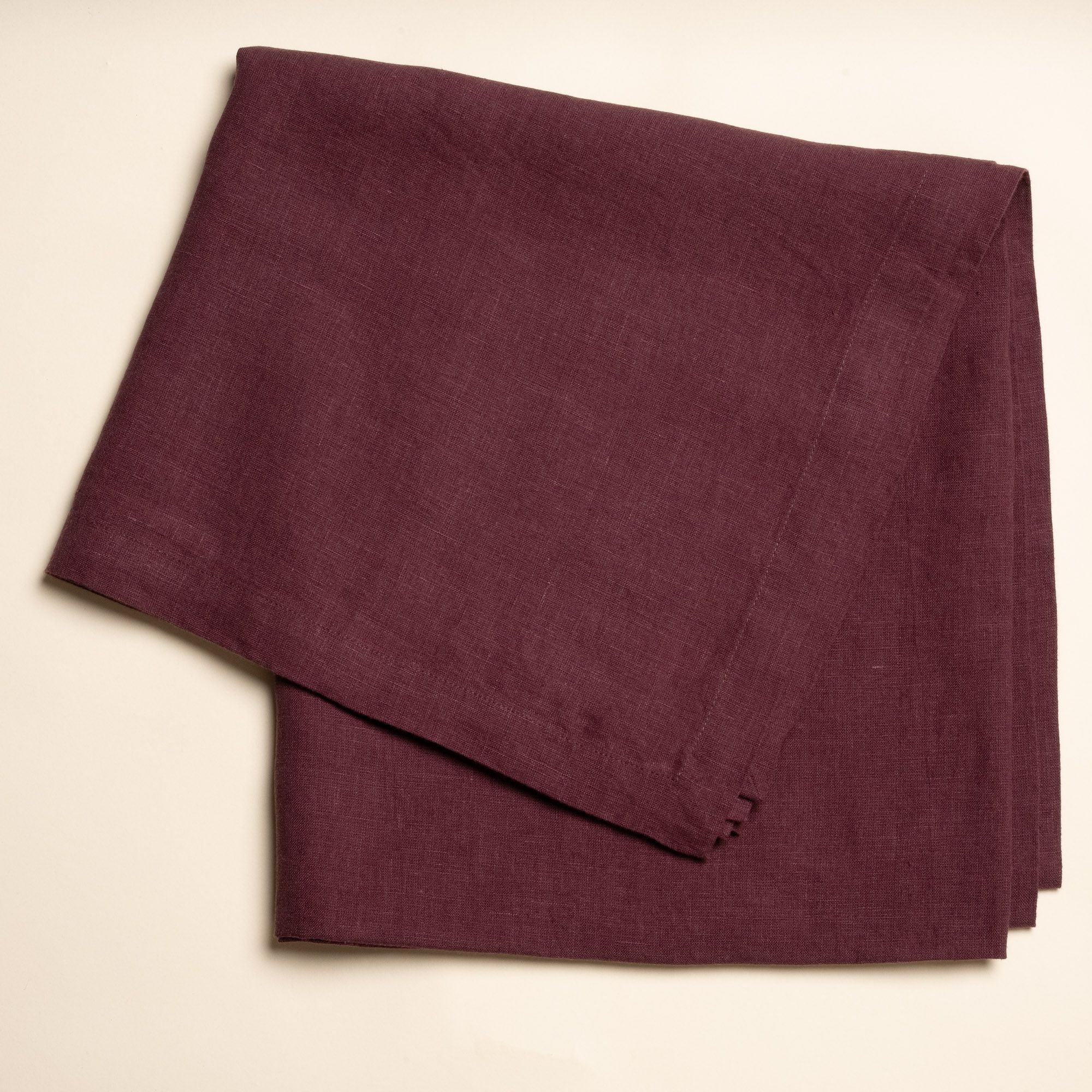 A folded linen tablecloth in a deep purple color
