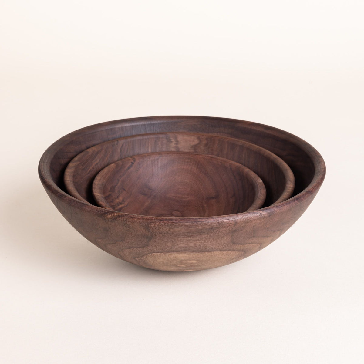 3 round walnut bowls nesting together in small, medium, and large sizes.