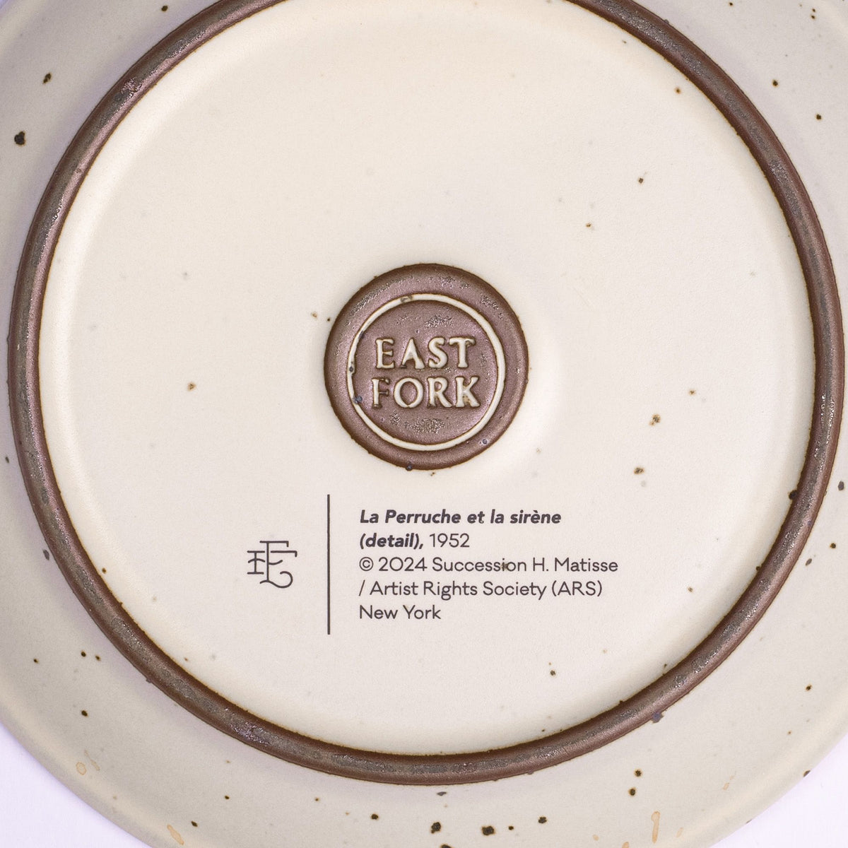 The back of a ceramic cake plate with an East Fork stamp with a small decal of information about the artwork.