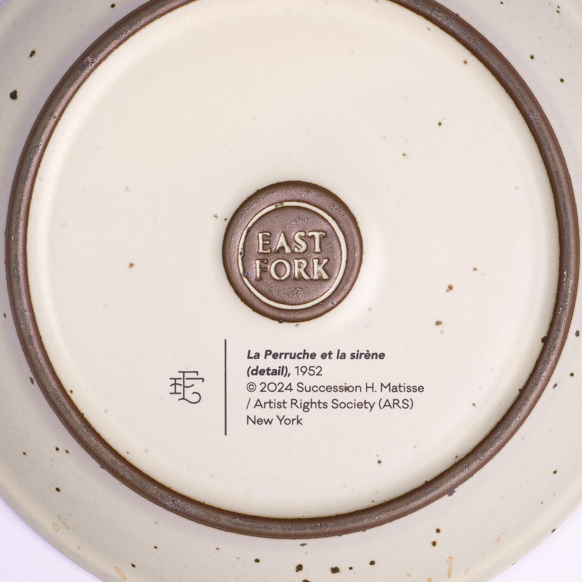 The back of a ceramic cake plate with an East Fork stamp with a small decal of information about the artwork.