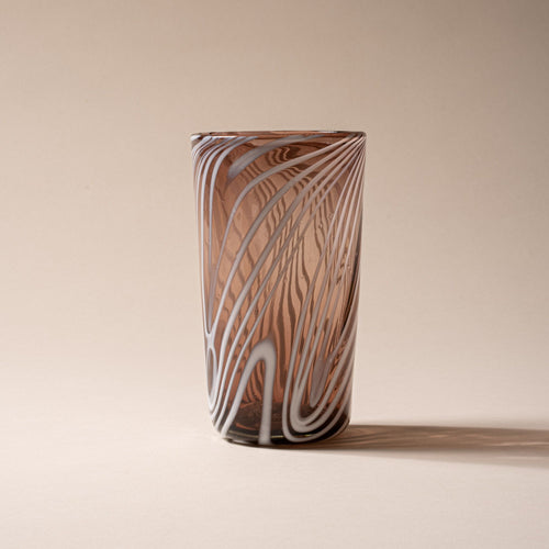 Smoky brown pint glass with white diagonal swirl pattern on a neutral background.