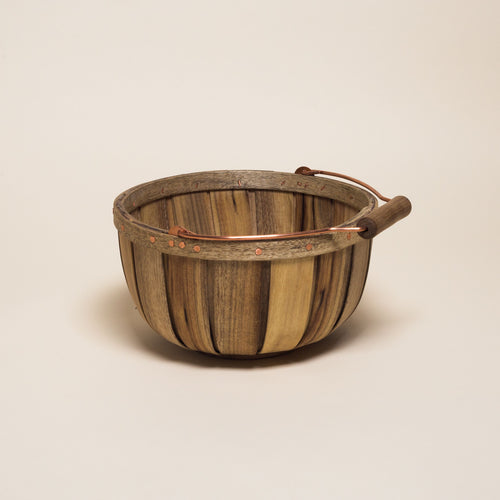 A large short round wooden basket with a metal and wood handle