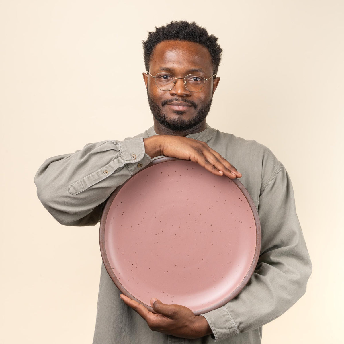 Demonta' holds a large ceramic serving platter in a dusty mauve pink color.