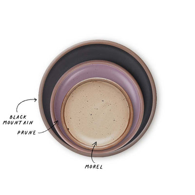 A stack of 3 plates in Dinner, Side, and Cake sizes in a black, soft mauve purple, and warm pale brown colors.