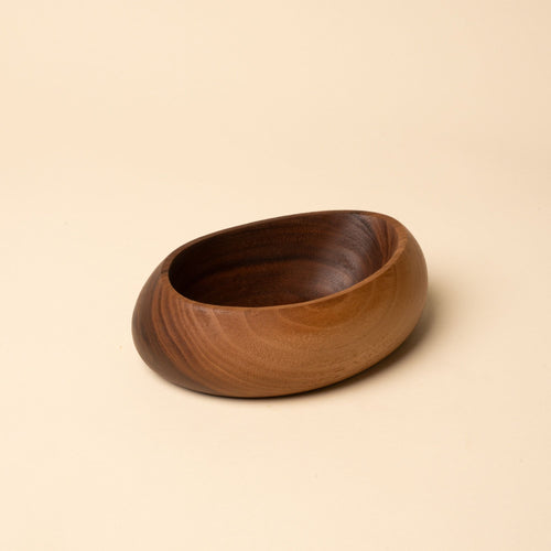 Carved wooden bowl with a smooth, rounded shape and rich brown grain, set against a neutral background.